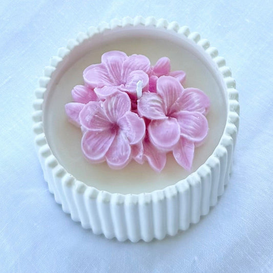 Bomboniera artigianale candela in cera di soia naturale con fiore di plumeria rosa in rilievo, ideale per matrimoni ed eventi