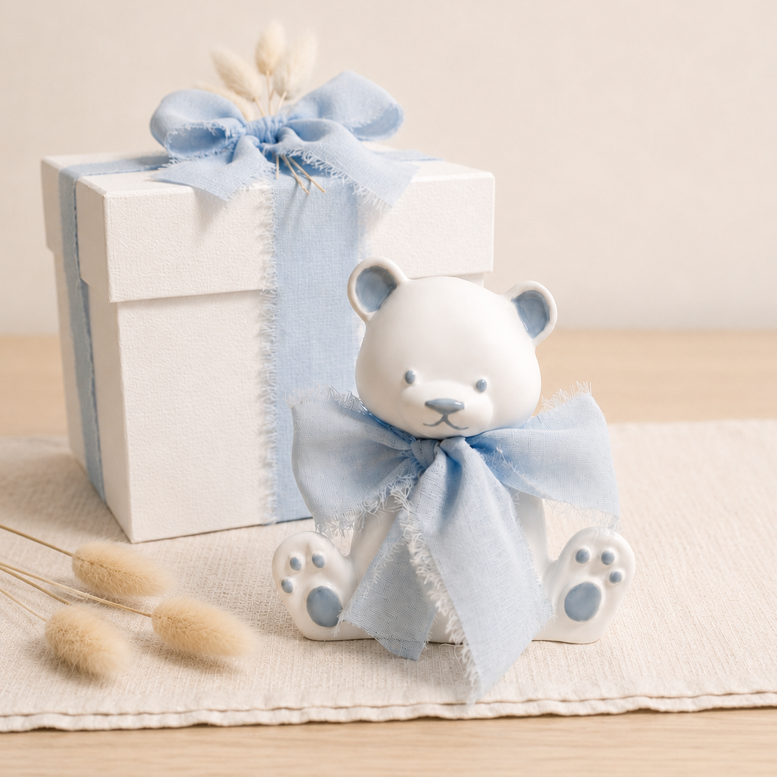 Bomboniera artigianale a forma di orsetto in ceramica con dettagli azzurri e nastro in chiffon azzurro, ideale per baby shower, nascita, battesimo