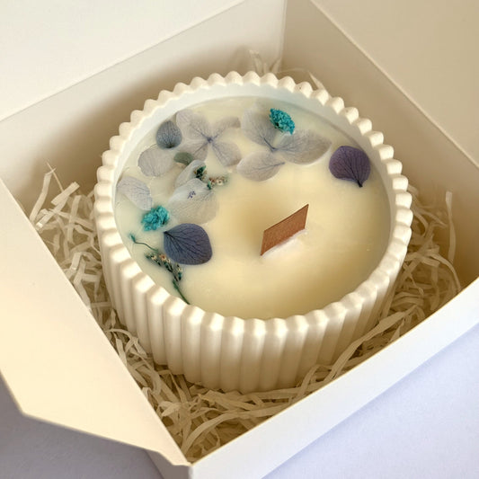 Bomboniera candela decorativa artigianale in cera di soia con fiori essiccati azzurri in contenitore di resina minerale