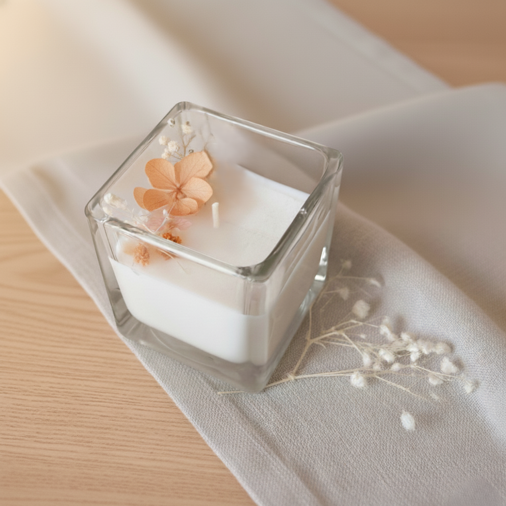 Candela botanica artigianale in cera di soia con fiori essiccati arancioni in contenitore quadrato di vetro, bomboniera elegante per matrimoni ed eventi